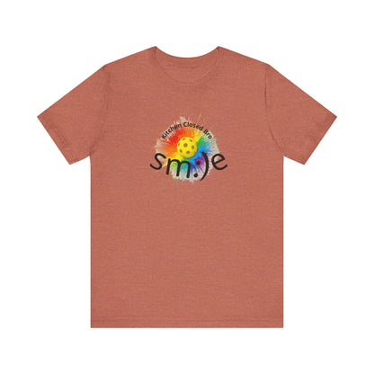 Brown t-shirt with a colorful smiley face design on a white background