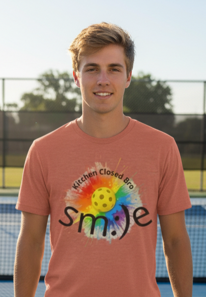Person wearing a pink t-shirt with a colorful graphic and text outdoors.